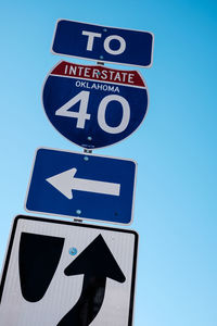 Low angle view of road sign against clear blue sky