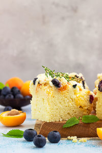 Blueberry and apricot crumble cake decorated with thyme on wooden board. 