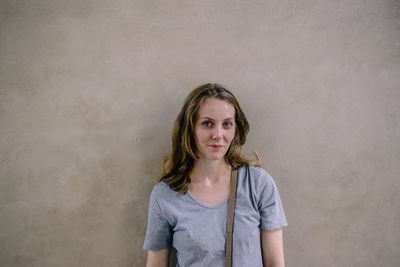 Portrait of beautiful young woman standing against wall