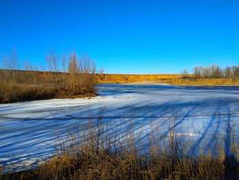 Scenic view of frozen lake against clear blue sky