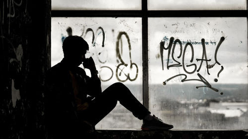 Side view of silhouette woman against graffiti wall