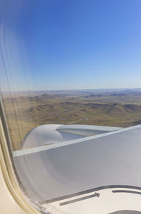 Low angle view of airplane wing over landscape