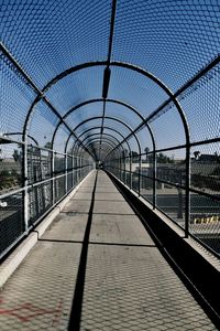 Bridge against clear sky seen through chainlink fence