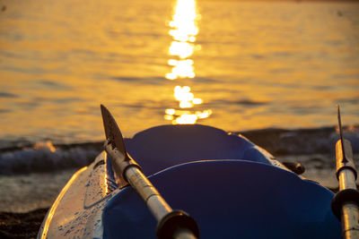 Close-up of illuminated ship at beach against sky during sunset