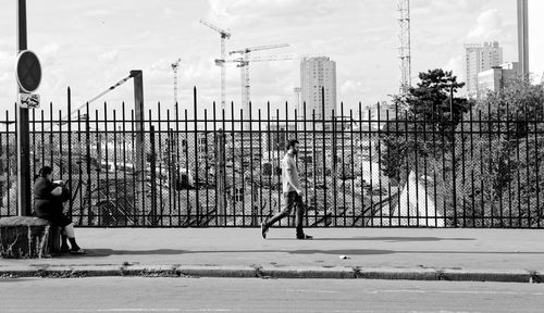 Man playing basketball against sky in city