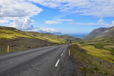 Road leading towards mountains against sky