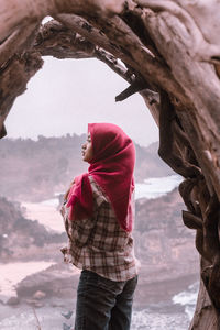 Woman wearing hijab standing below natural arch