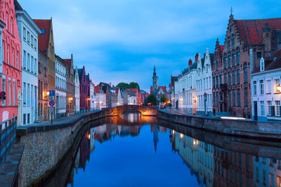 Canal amidst buildings in city against sky at dusk