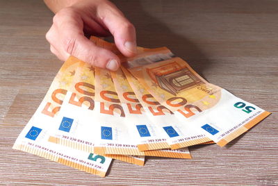 Close-up of hand holding paper with text on table