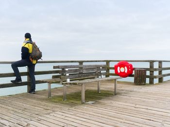 Rear view of man on pier against sky