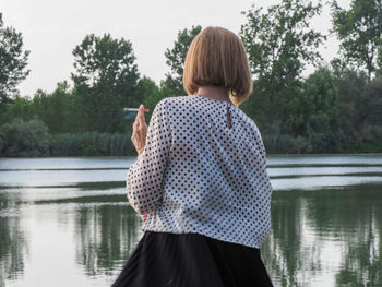 Rear view of woman standing against lake