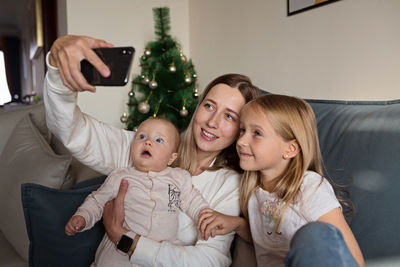 Happy mother doing selfie with kids at home