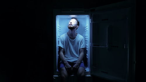 Portrait of man sitting in fridge