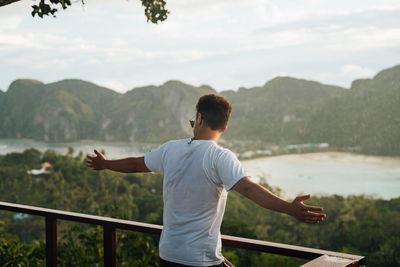 Rear view of man looking at mountains against sky