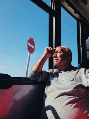 PORTRAIT OF MAN HOLDING MOBILE PHONE WHILE SITTING IN BUS
