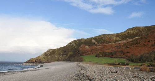 Scenic view of beach and mountains against sky