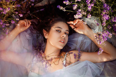 Portrait of young woman lying down on flowering plant