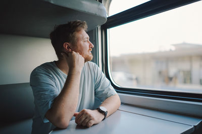 A man in a blue t-shirt while traveling by railway train