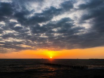 Scenic view of sea against dramatic sky during sunset