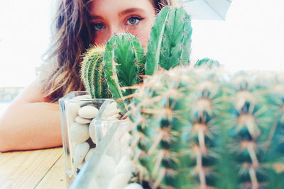 Close-up portrait of young woman by cactus