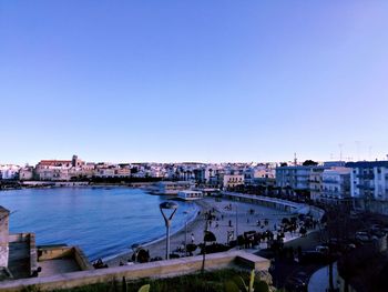 High angle view of river and buildings against clear blue sky