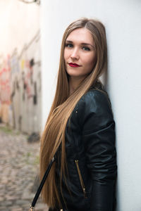 Portrait of beautiful woman standing by wall