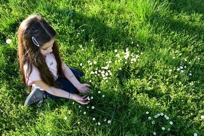 Girl looking at flowering plants on field