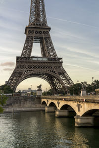 Eiffel tower by river seine in city against sky