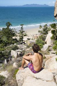 Rear view of shirtless man looking at sea