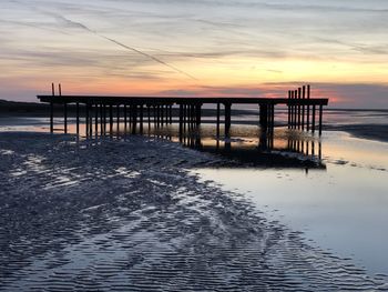 Pier on sea against sky during sunset