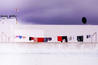 Clothes hanging on snow against sky at dusk