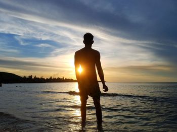 Silhouette man standing at beach during sunset