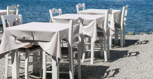 Empty chairs and tables and table by sea