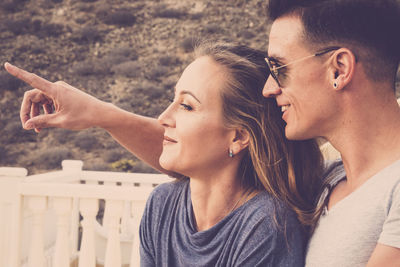 Close-up of man pointing while sitting with girlfriend outdoors