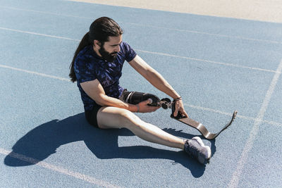 Athlete with prosthetic leg sitting on sports track