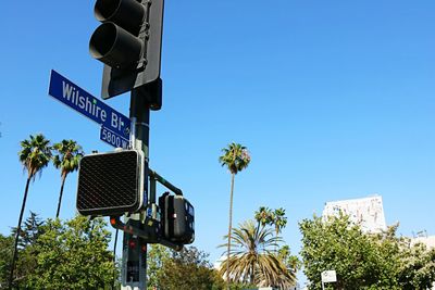 Low angle view of road sign against clear blue sky