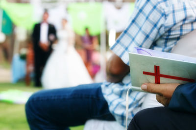 Midsection of man holding book