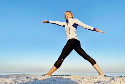 Woman with arms outstretched against clear sky