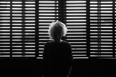 Rear view of woman standing against wall