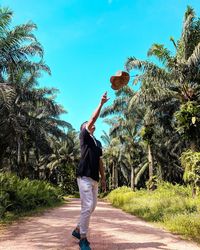 Full length of man throwing hat while standing on road in park