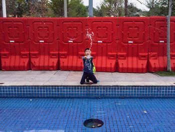 Full length of woman standing by swimming pool