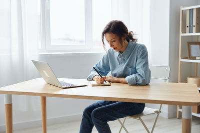 Businesswoman writing in diary at office