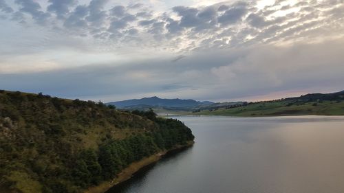 Scenic view of river by mountains against sky
