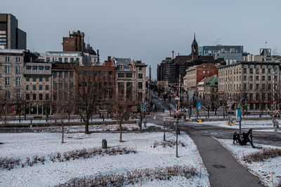 Buildings in city against clear sky during winter