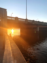 Bridge over road against sky during sunset