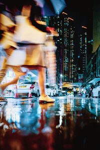 Blurred motion of man on illuminated street against buildings at night