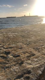 Surface level of beach against sky during sunset