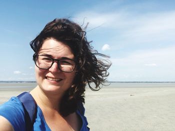 Portrait of smiling woman at beach against sky