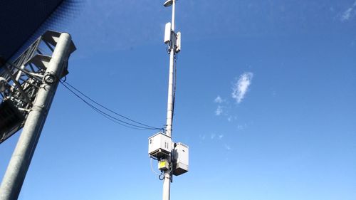 Low angle view of telephone pole against blue sky