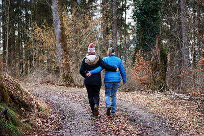 Rear view of women walking on footpath in forest